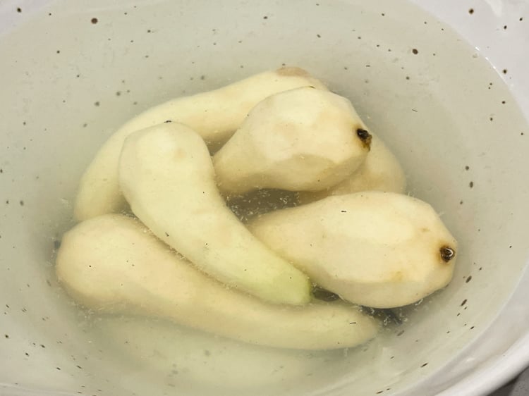 skalade päron i skål med vatten